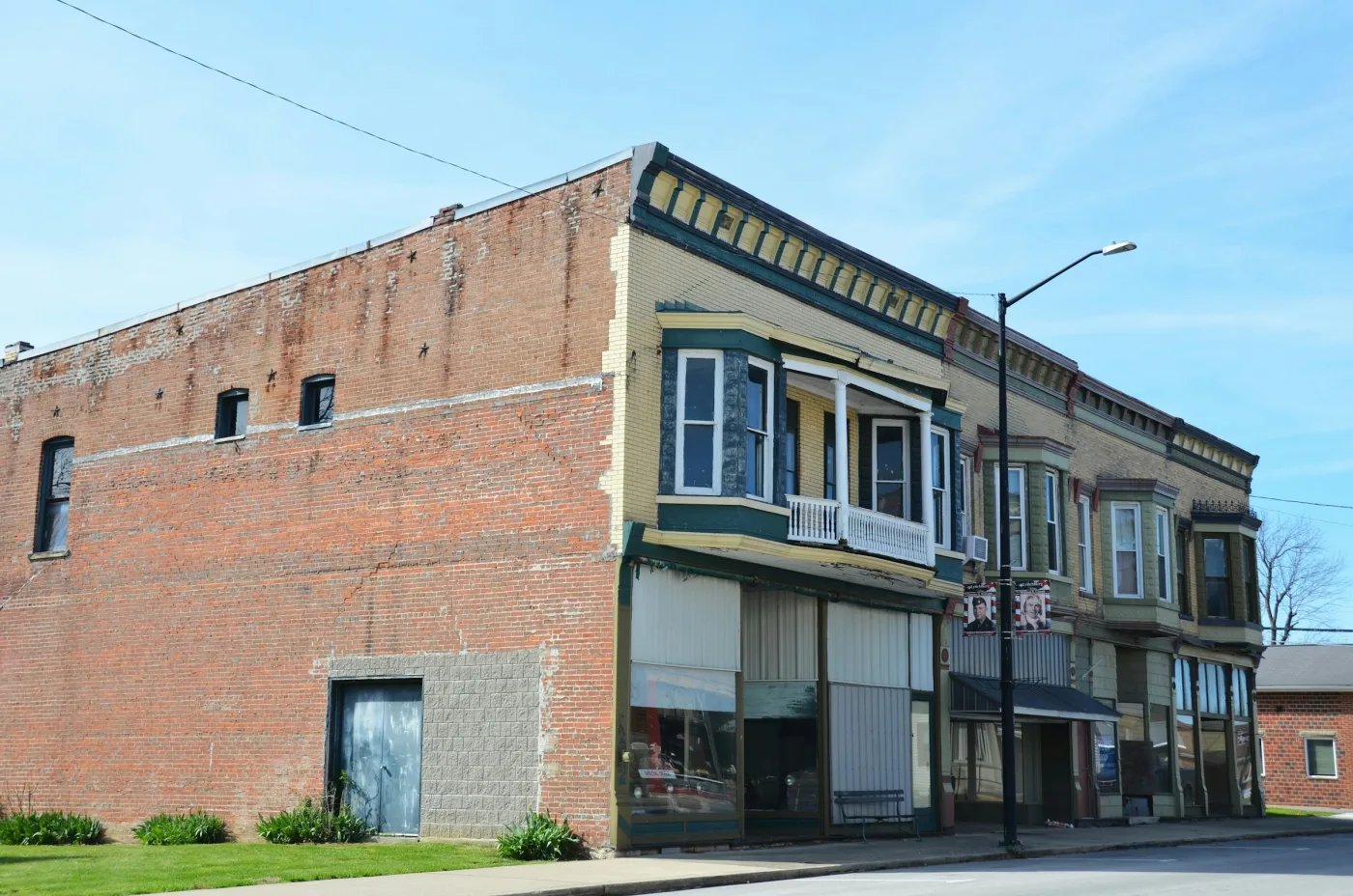 Sunlight on the brickwork and bay windows of a historic corner storefront.