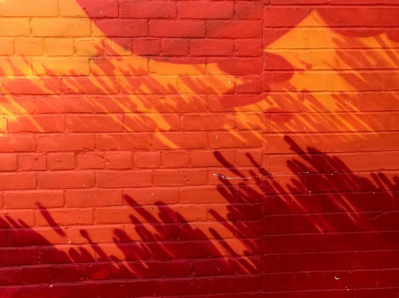 Overlapping red and orange geometric shapes painted across a brick wall.