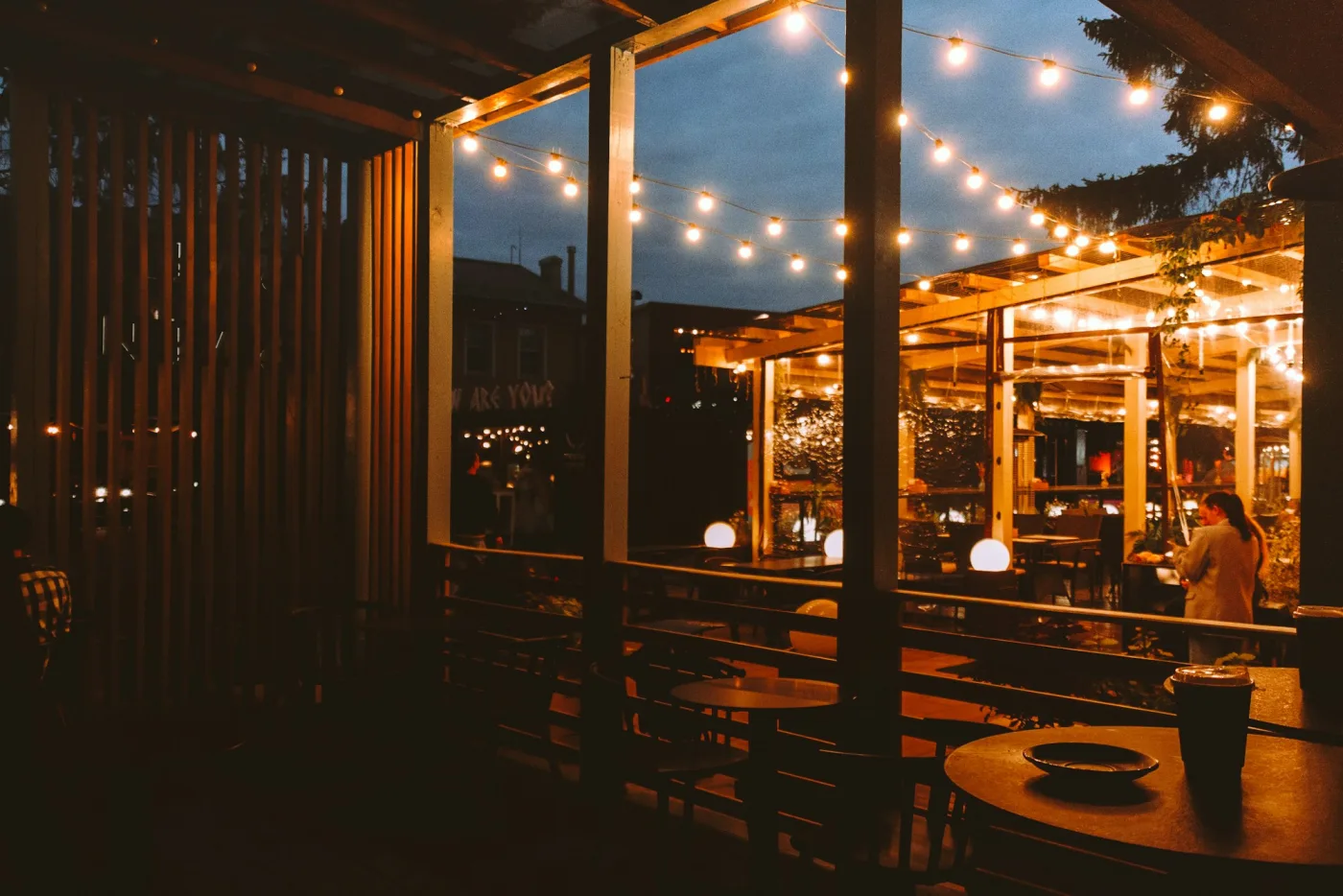An inviting restaurant patio with string lights overhead at dusk.