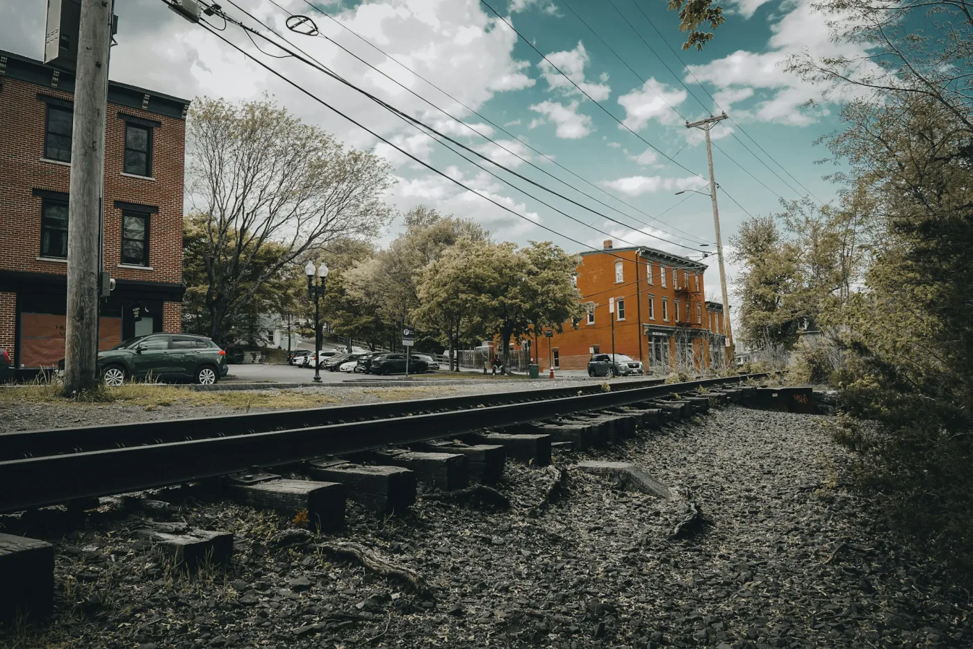 Old railway tracks tracing a route beside historic brick industrial buildings.